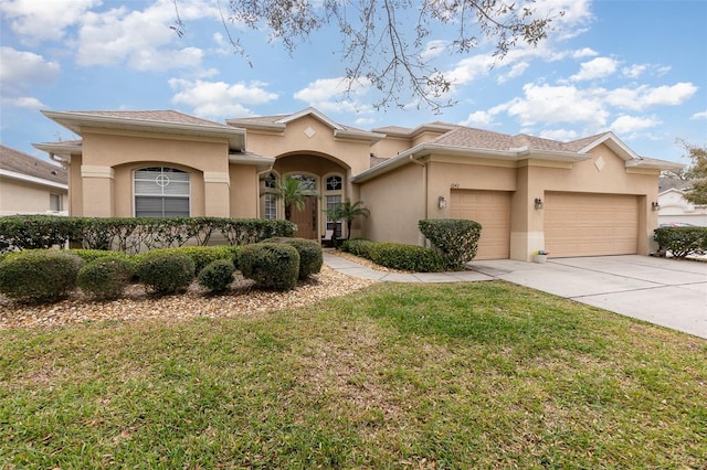 mediterranean / spanish home with an attached garage, stucco siding, driveway, and a front yard