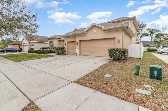 view of front of property with a garage, fence, concrete driveway, and stucco siding