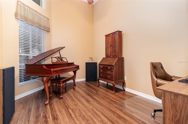 office area with a high ceiling, baseboards, and wood finished floors