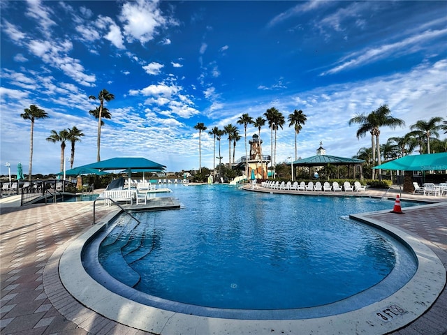 pool with a water slide, a patio area, and a gazebo