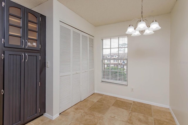 interior space with a textured ceiling, baseboards, and a notable chandelier