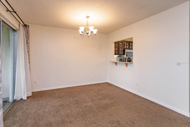 spare room with a notable chandelier, a textured ceiling, baseboards, and carpet flooring