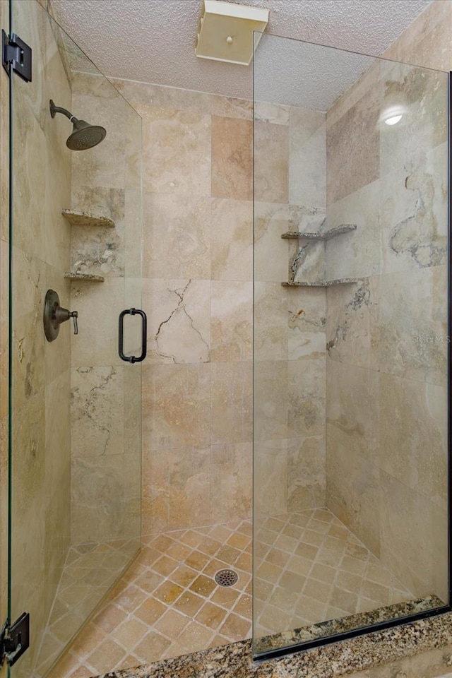 full bathroom with a stall shower and a textured ceiling