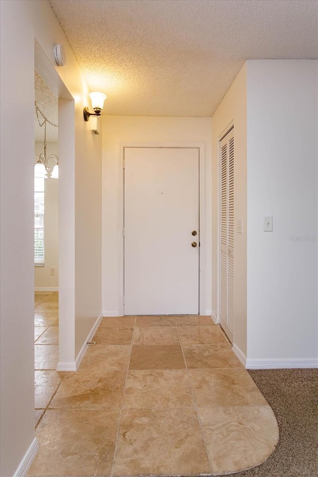 corridor with a textured ceiling and baseboards