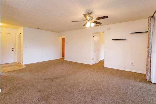 carpeted spare room with ceiling fan, baseboards, and a textured ceiling