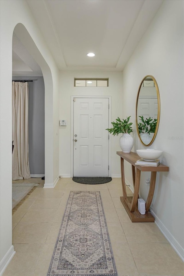 doorway to outside with arched walkways, recessed lighting, baseboards, and light tile patterned floors