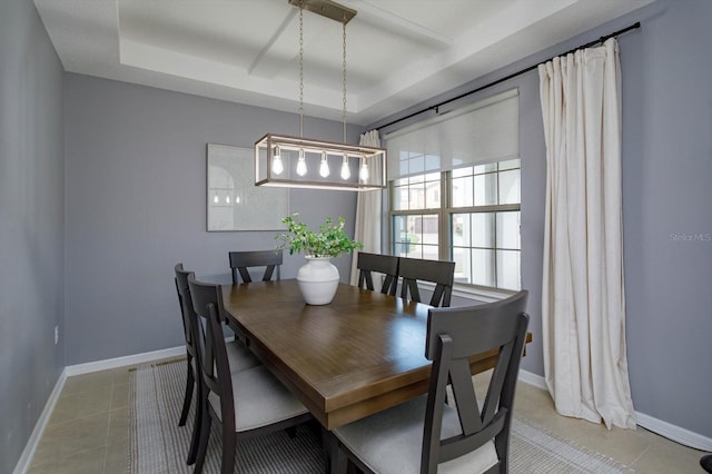 dining space featuring light tile patterned floors, a raised ceiling, and baseboards