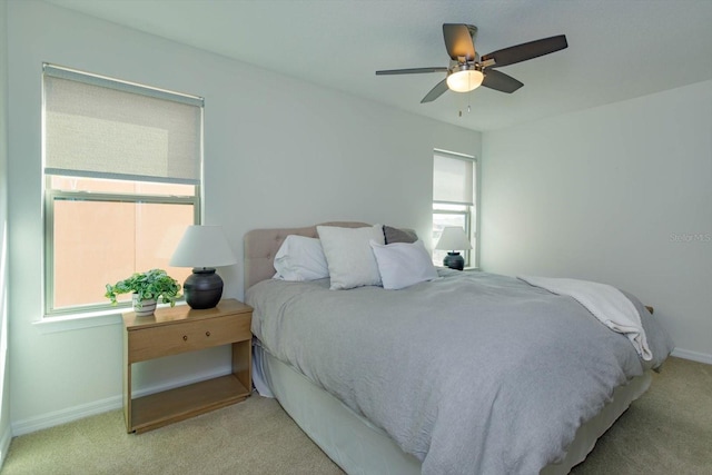 bedroom with baseboards, multiple windows, a ceiling fan, and light colored carpet