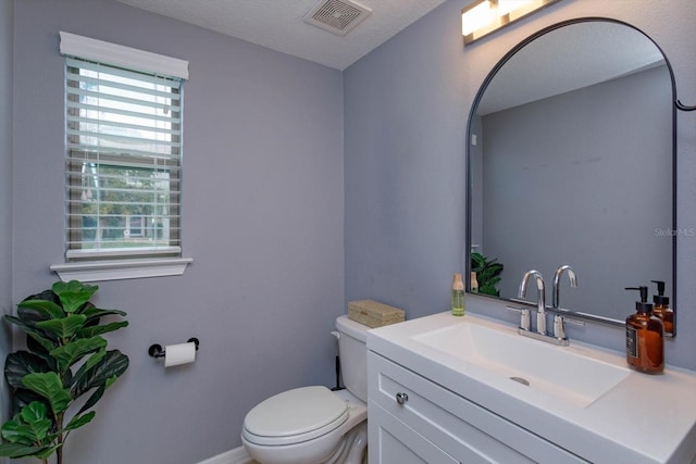 bathroom with toilet, baseboards, visible vents, and vanity