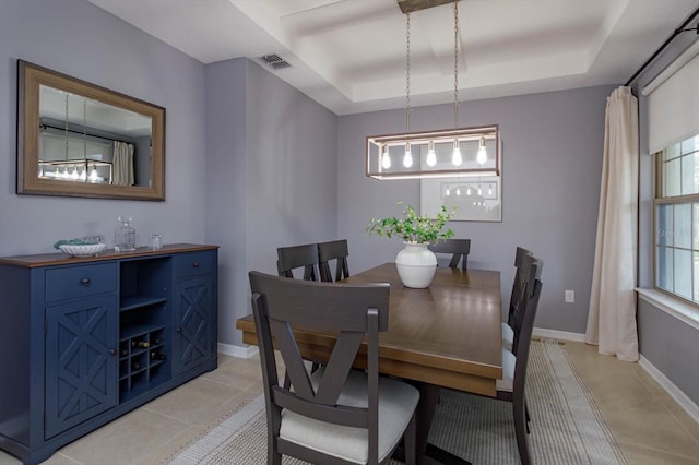 dining space with a tray ceiling, visible vents, baseboards, and light tile patterned floors