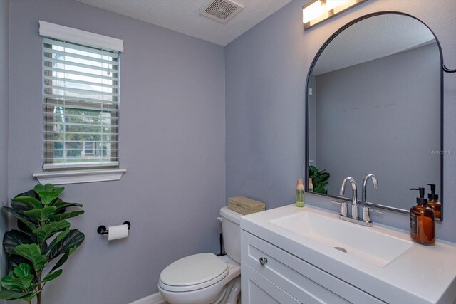 bathroom with baseboards, visible vents, vanity, and toilet