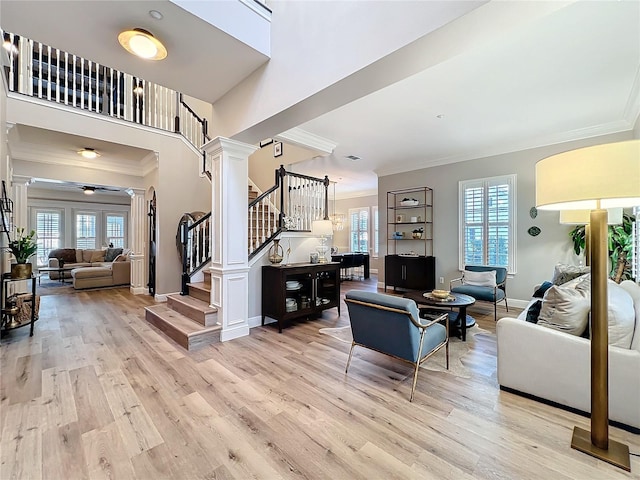 living room featuring baseboards, stairs, ornamental molding, light wood-type flooring, and ornate columns