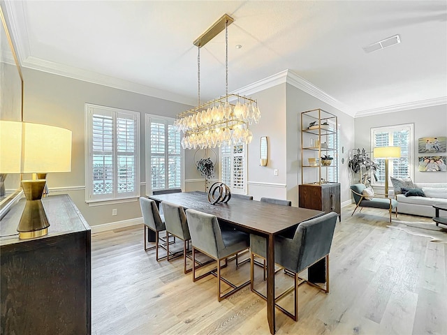 dining space featuring ornamental molding, light wood-style flooring, and a healthy amount of sunlight