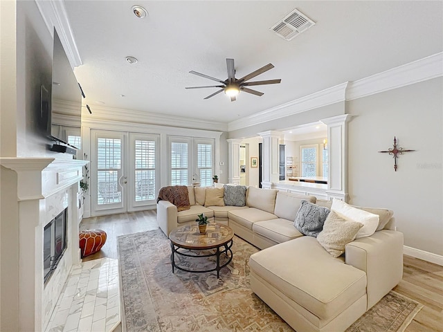 living area featuring french doors, decorative columns, visible vents, a high end fireplace, and light wood-type flooring