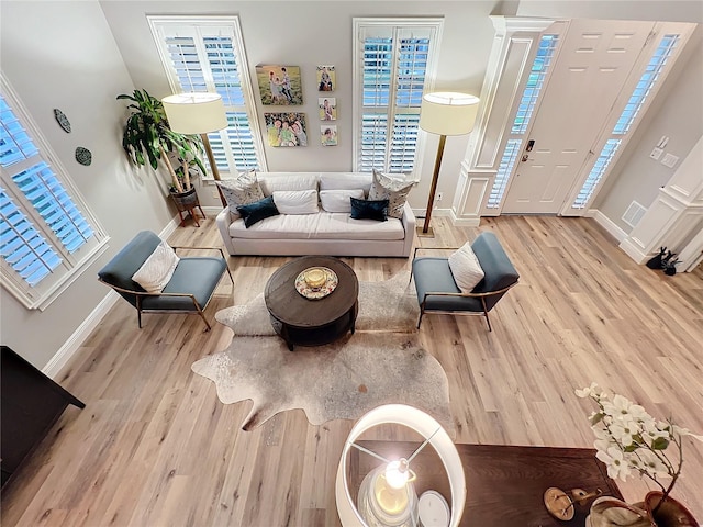 living room featuring visible vents, baseboards, and wood finished floors