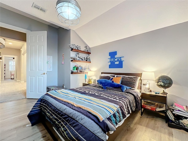 bedroom featuring visible vents, vaulted ceiling, and wood finished floors