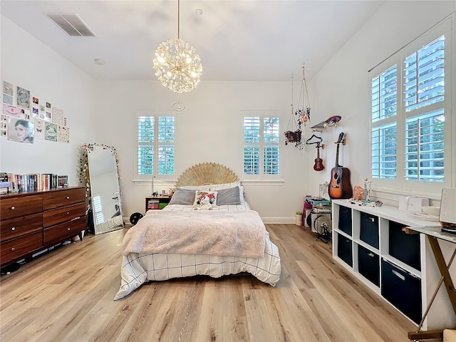 bedroom featuring a notable chandelier, baseboards, visible vents, and light wood-style floors