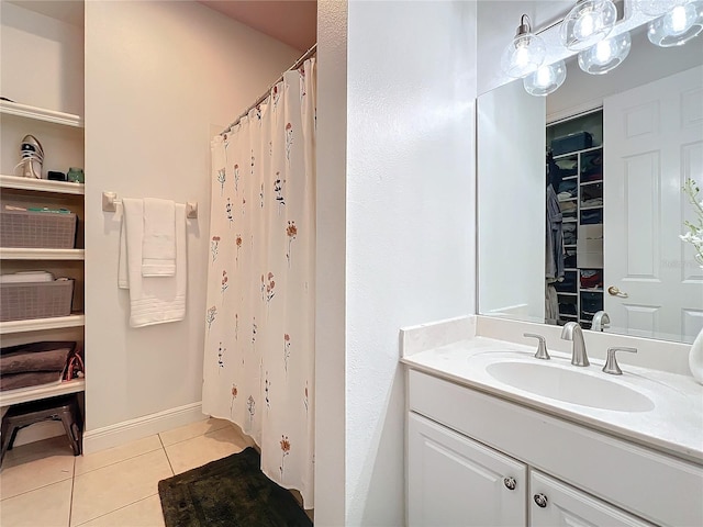 full bathroom with a shower with shower curtain, vanity, baseboards, tile patterned floors, and a walk in closet