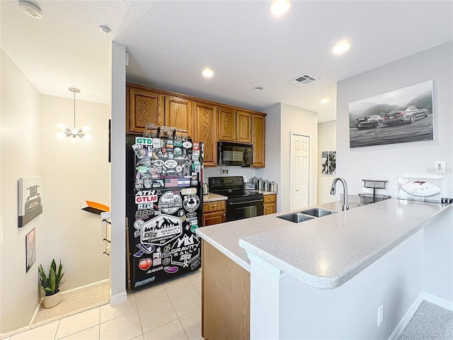 kitchen featuring a peninsula, a sink, visible vents, black appliances, and brown cabinetry