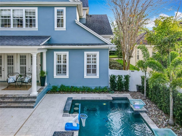 rear view of house featuring a shingled roof, a fenced in pool, fence, and stucco siding