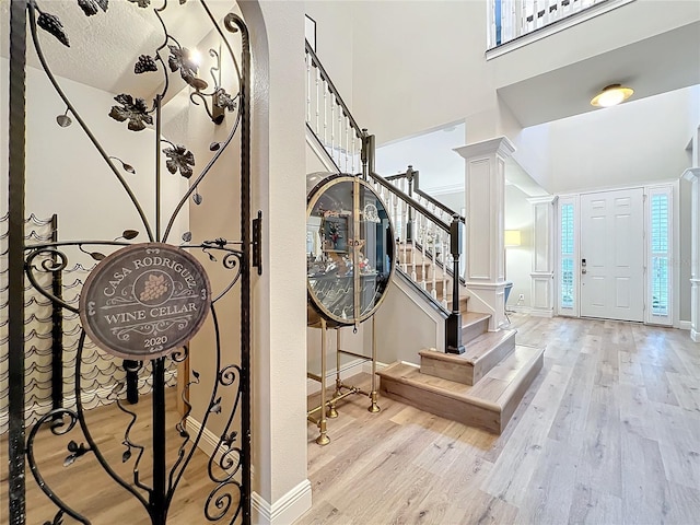 entrance foyer featuring decorative columns, a high ceiling, stairway, and wood finished floors