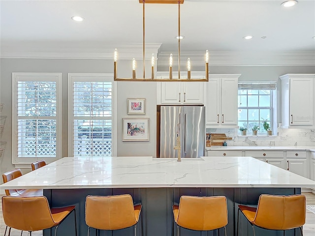 kitchen with tasteful backsplash, crown molding, white cabinets, and high end fridge