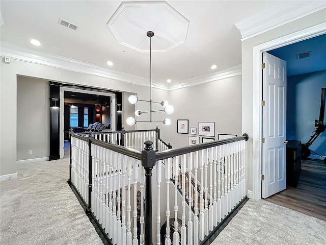 hallway with carpet floors, an upstairs landing, visible vents, and ornamental molding