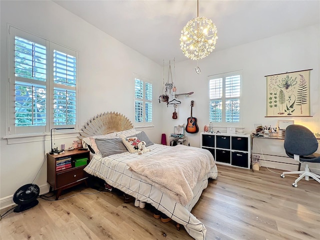 bedroom with a chandelier, baseboards, and wood finished floors