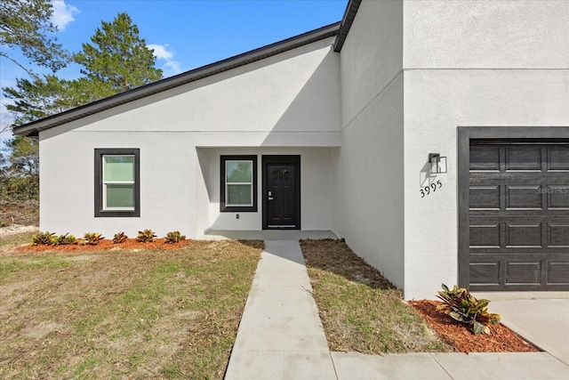 view of exterior entry with a garage and stucco siding