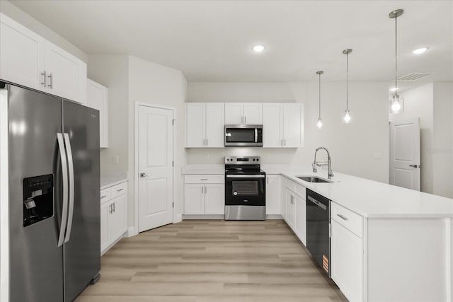 kitchen featuring white cabinets, light wood-style flooring, appliances with stainless steel finishes, a peninsula, and a sink