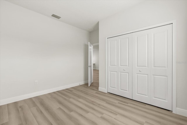 unfurnished bedroom with a closet, light wood-type flooring, visible vents, and baseboards