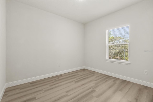 unfurnished room with light wood-type flooring and baseboards