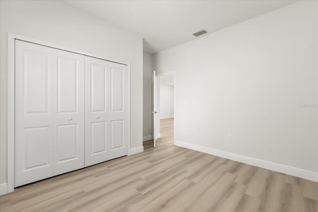 unfurnished bedroom with visible vents, a closet, light wood-style flooring, and baseboards