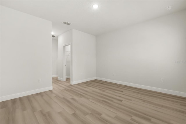 empty room with light wood-type flooring, baseboards, and visible vents