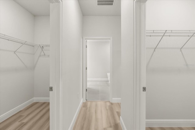 walk in closet with light wood finished floors and visible vents