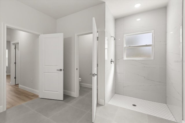 full bath with toilet, a marble finish shower, and baseboards