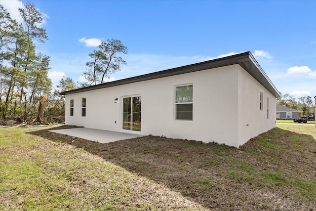 back of house with a patio area, stucco siding, and a yard