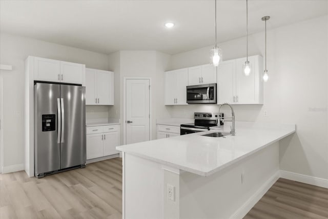 kitchen featuring stainless steel appliances, white cabinetry, a sink, light wood-type flooring, and a peninsula