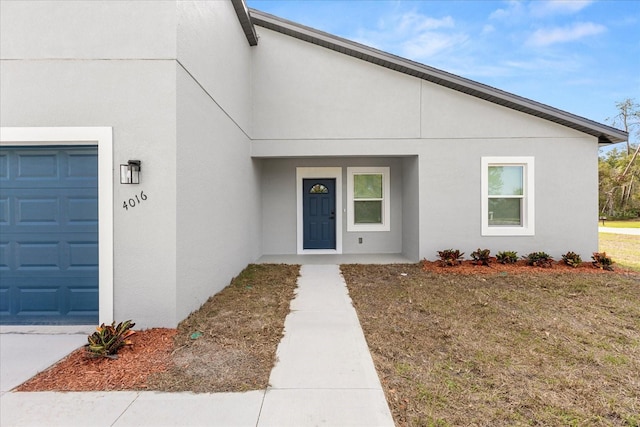 entrance to property with an attached garage and stucco siding