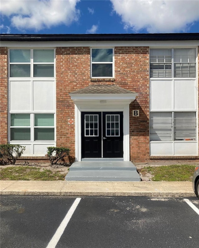 doorway to property with uncovered parking and brick siding