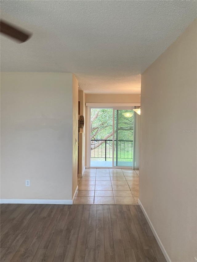 hall featuring a textured ceiling, baseboards, and wood finished floors