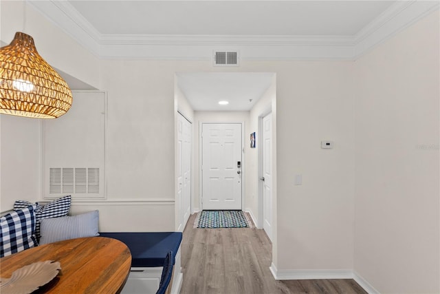 entrance foyer featuring baseboards, crown molding, visible vents, and wood finished floors