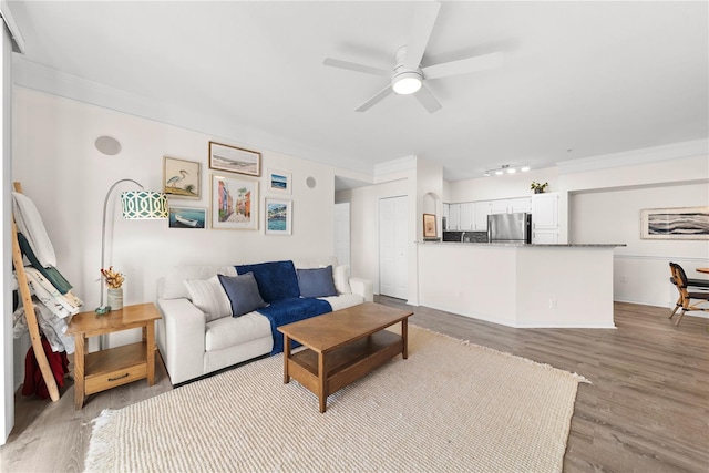 living room featuring ornamental molding, ceiling fan, and light wood finished floors