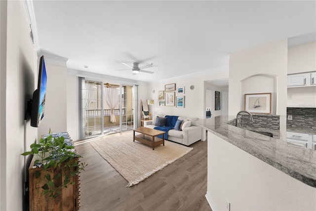 living area featuring dark wood-style floors, ceiling fan, and crown molding