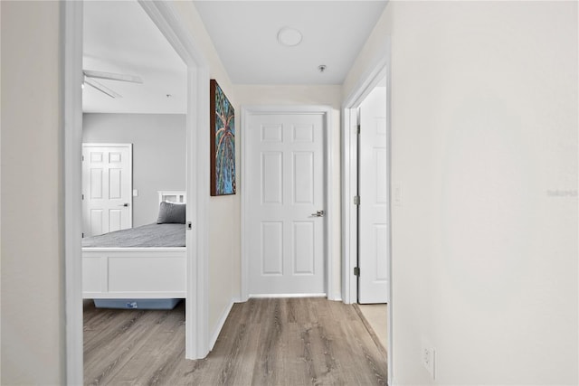 hallway with light wood-type flooring and baseboards