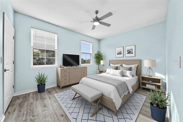 bedroom featuring light wood finished floors, baseboards, and a ceiling fan