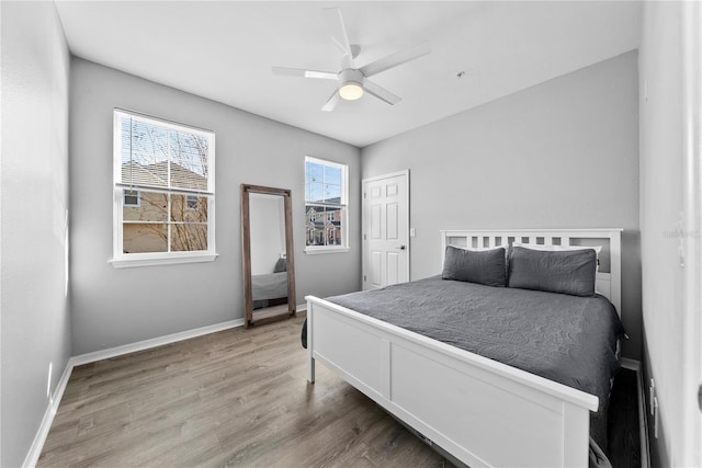 bedroom with a ceiling fan, baseboards, and wood finished floors