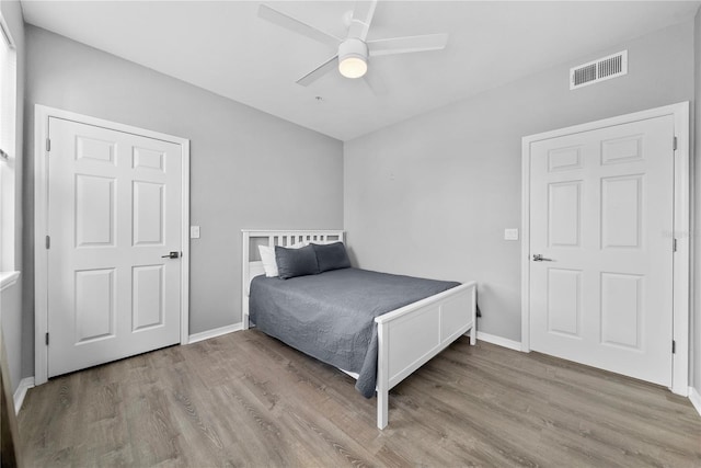 bedroom with light wood-type flooring, baseboards, visible vents, and a ceiling fan