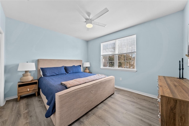 bedroom featuring ceiling fan, baseboards, and wood finished floors