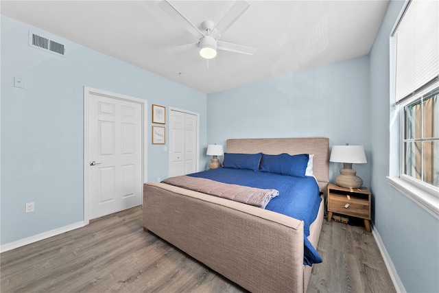 bedroom with light wood finished floors, baseboards, visible vents, and a closet